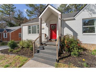 Charming white home with a bright red front door and manicured landscaping and gray steps at 1784 Terry Mill Se Rd, Atlanta, GA 30316
