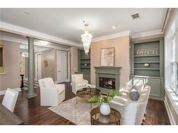 Bright living room featuring a fireplace, chandelier, hardwood floors, and built-in bookshelves at 3280 Stillhouse Se Ln # 108, Atlanta, GA 30339