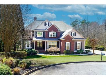 Charming two-story home with a brick and gray exterior, lush lawn, and manicured landscaping creates excellent curb appeal at 203 Glenrise Ct, Woodstock, GA 30188