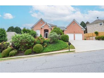 Charming red brick home with a manicured front yard and a two-car garage on a picturesque street at 11385 Donnington Dr, Duluth, GA 30097