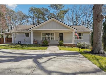 Charming home featuring a covered porch, manicured lawn, and an expansive driveway at 596 Frank Kirk Nw Rd, Kennesaw, GA 30152