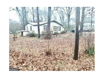 A quaint, single-story home surrounded by a yard full of fallen leaves and mature trees at 6385 Gordon St, Lithia Springs, GA 30122