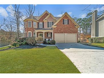 Charming two-story red brick home featuring a well-manicured lawn and an attached two-car garage at 1654 Summersweet Ln, Dacula, GA 30019