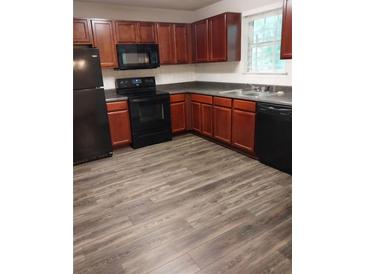 Traditional kitchen featuring wood cabinets, black appliances, and laminate floors at 5175 Hanover St, Atlanta, GA 30349