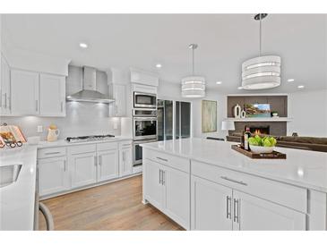 Modern kitchen with white cabinets, stainless steel appliances, and a large island with white countertop at 935 Tiber Cir, Alpharetta, GA 30022