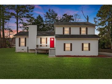 Charming two-story home features a red front door, green lawn, and traditional shutters at 712 Berts Nw Cir, Lilburn, GA 30047