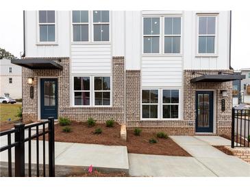 Modern townhome featuring brick and white siding, black awnings and window frames, and manicured landscaping at 337 Skylar Se Way, Atlanta, GA 30315