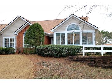 Charming home featuring a manicured lawn, brick accents, and a welcoming front entrance with lush greenery at 3787 Vineyards Lake Nw Cir # 21, Kennesaw, GA 30144