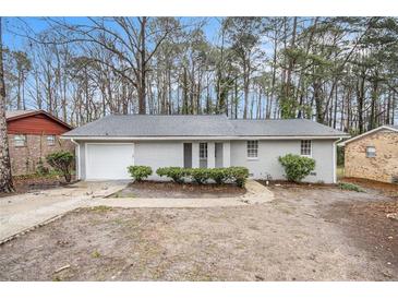 Charming, light gray brick ranch-style home with attached garage and mature trees in a serene setting at 6510 Connell Rd, Atlanta, GA 30349