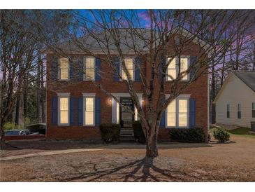 Charming two-story brick home with blue shutters and a well-maintained front yard surrounded by mature trees at 1370 Wheatfield Dr, Lawrenceville, GA 30043