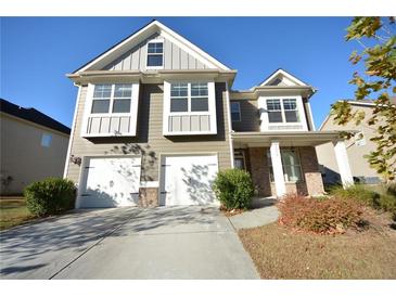 Inviting two-story home with a two-car garage, manicured shrubs, and neutral siding under a clear sky at 2453 Osceola Rd, Lithonia, GA 30058