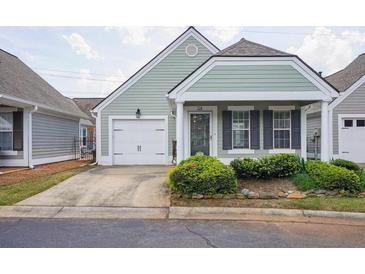 Charming, light-green, single-story home featuring a well-manicured yard and attached one-car garage at 134 Rose Cottage Ln, Woodstock, GA 30189