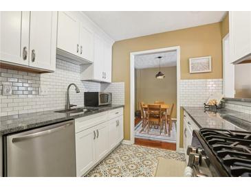 Bright kitchen featuring white cabinets, subway tile backsplash, granite countertops, and stainless steel appliances at 101 Natchez Trce, Atlanta, GA 30350