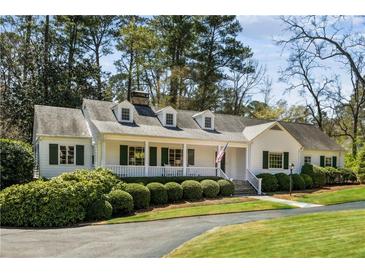 Charming single-story home boasts a white picket fence, manicured lawn, and inviting front porch at 1664 West Wesley Nw Rd, Atlanta, GA 30327
