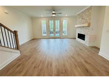 Bright, open living room with hardwood floors, stone fireplace, and French doors leading to the outdoors at 2400 Edgar Park Pl # 103, Duluth, GA 30096