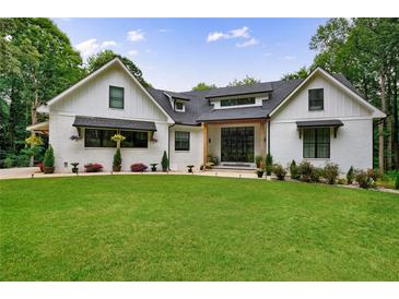 Stunning white brick home with a lush green lawn and meticulously landscaped flower beds at 836 Bailey Woods Rd, Dacula, GA 30019