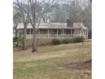 Charming ranch-style home featuring a long porch, metal roof, and a stone chimney at 582 S Cherokee Rd, Social Circle, GA 30025