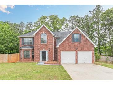 Charming two-story brick home featuring a two-car garage, manicured lawn, and a classic, welcoming facade at 105 Kentwood Springs Dr, Hampton, GA 30228