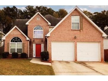 Charming two-story brick home with a well-manicured lawn, attached two car garage and a bright red front door at 11532 Ethan Ct, Hampton, GA 30228