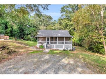 Charming cottage-style home featuring a screened front porch and a lush, wooded lot at 4481 Mclain Cir, Acworth, GA 30101