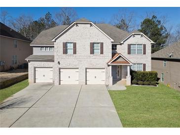 Charming two-story brick home featuring a three-car garage and well-manicured lawn at 7686 Brazos Trl, Fairburn, GA 30213