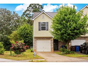 Charming townhome with brick accents, a one-car garage and a well-maintained front yard with lush greenery at 905 Magnolia Gardens Walk, Mcdonough, GA 30253