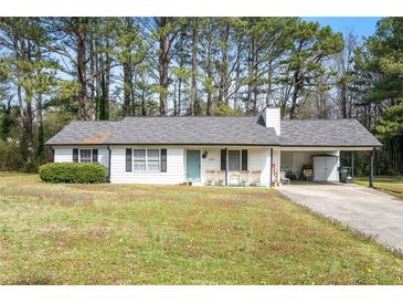 Charming single-story home with a light blue door, a covered carport, and a well-maintained front yard at 2921 Oakwilde Ct, Snellville, GA 30039