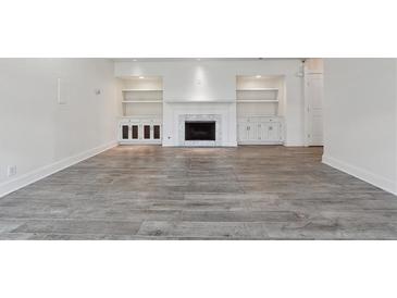 Bright living room featuring a fireplace, built-in shelving, and wood-look flooring at 3636 Peachtree Ne Rd # 405, Atlanta, GA 30319