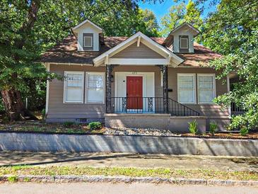 Charming home with a red front door, dormer windows, and a wrought iron railing on the covered front porch at 673 Pearce Sw St, Atlanta, GA 30310