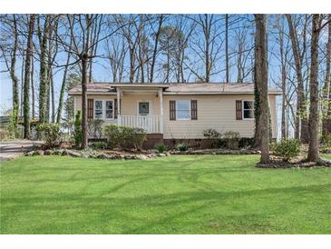 Charming single-story home with a well-manicured lawn and mature trees providing shade at 881 Brighton Dr, Lawrenceville, GA 30043