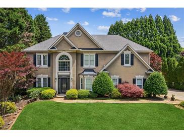 Charming two-story home featuring manicured landscaping, lush lawn, and mature trees at 2115 Brook Pond Ct, Alpharetta, GA 30005