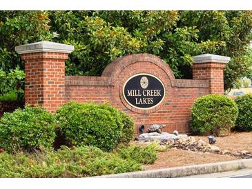 Brick community sign for Mill Creek Lakes with lush green landscaping and decorative rock features at 3032 Cedar Glade Ln, Buford, GA 30519