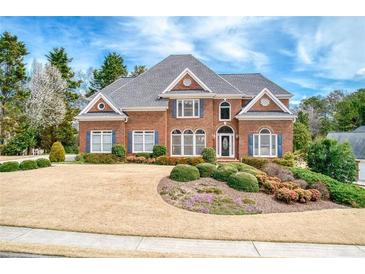 Beautiful brick home with manicured front lawn and mature landscaping on a sunny day at 720 First Cotton Dr, Powder Springs, GA 30127