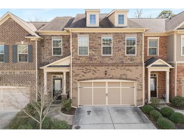 Exterior of a brick townhome featuring a two-car garage, covered entrance, and well-maintained landscaping at 2286 Emerald Sky Dr, Smyrna, GA 30080