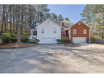 Inviting two-story home with attached garages and circular driveway nestled amongst mature trees at 3608 Stedman Pl, Duluth, GA 30096