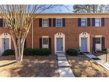Charming brick townhome with a manicured lawn and blue front doors at 2828 Webb Bridge Rd, Alpharetta, GA 30009