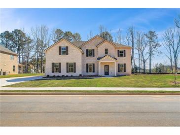 Charming two-story brick home featuring a manicured lawn and inviting front entrance at 209 Haverling Pass, Hampton, GA 30228