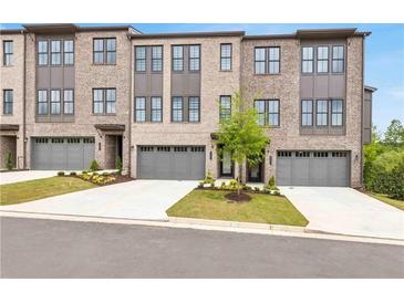 Charming brick townhomes boast individual garages and manicured lawns for a welcoming curb appeal at 557 Red Clay Farm Ln, Suwanee, GA 30024