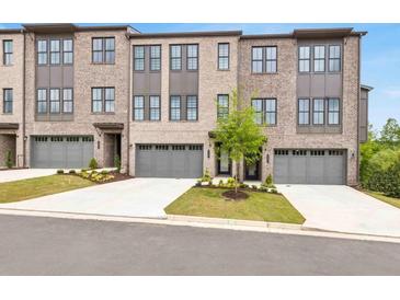 Modern brick townhomes feature attached garages, professional landscaping, and concrete driveways at 577 Red Clay Farm Ln, Suwanee, GA 30024