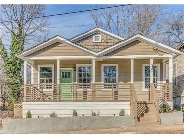 Charming home featuring tan siding, white trim, inviting front porch and a delightful green front door at 385 Arthur Sw St, Atlanta, GA 30310