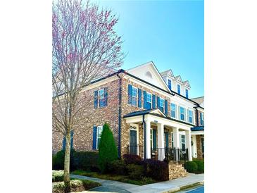 Charming brick townhome featuring blue shutters and a covered front porch, complemented by well-maintained landscaping at 475 Letchas Ln, Alpharetta, GA 30009