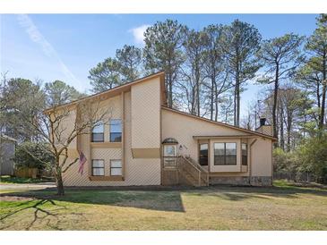 Two-story tan home with gable roof, brick facade, front porch, and manicured lawn at 425 Ridgemont Dr, Lawrenceville, GA 30046