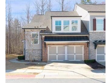 Charming townhome exterior showcases a two-car garage, stone accents, and well-maintained landscaping at 185 Bellehaven Dr, Woodstock, GA 30188