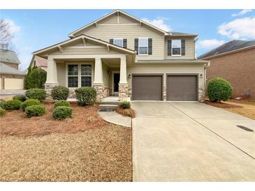 Charming two-story home features a well-manicured lawn, two-car garage and covered porch with stone accents at 12981 Dartmore Cir, Alpharetta, GA 30005