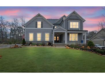 Charming two-story home with a well-manicured lawn and a welcoming front porch at dusk at 430 Parkbrook Way, Canton, GA 30114