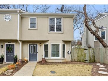 Charming townhome featuring a well-manicured front yard and neutral-tone facade, near a walkway and trees at 1002 Defoors Nw Lndg, Atlanta, GA 30318