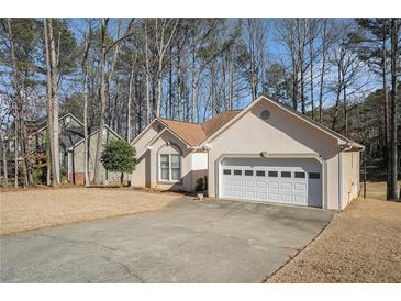 Charming single-story home with attached two-car garage and well-maintained lawn surrounded by mature trees at 606 Wedgewood Dr, Woodstock, GA 30189
