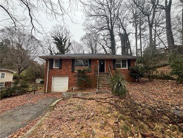 Traditional brick home featuring a front-facing garage, black shutters, and steps leading to the front door at 1900 Calloway Nw Dr, Atlanta, GA 30314