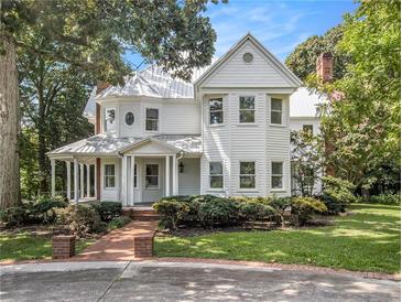 Charming two-story white home with a metal roof, front porch, brick walkway and mature landscaping at 5809 Warren Farm Sw Rd, Powder Springs, GA 30127