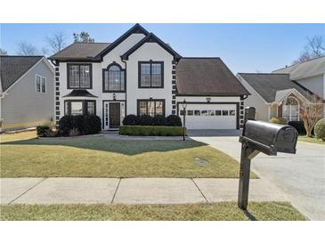 Charming two-story home featuring black and white trim, a well-manicured lawn, and an attached two-car garage at 2882 Manor Glen Ln, Suwanee, GA 30024